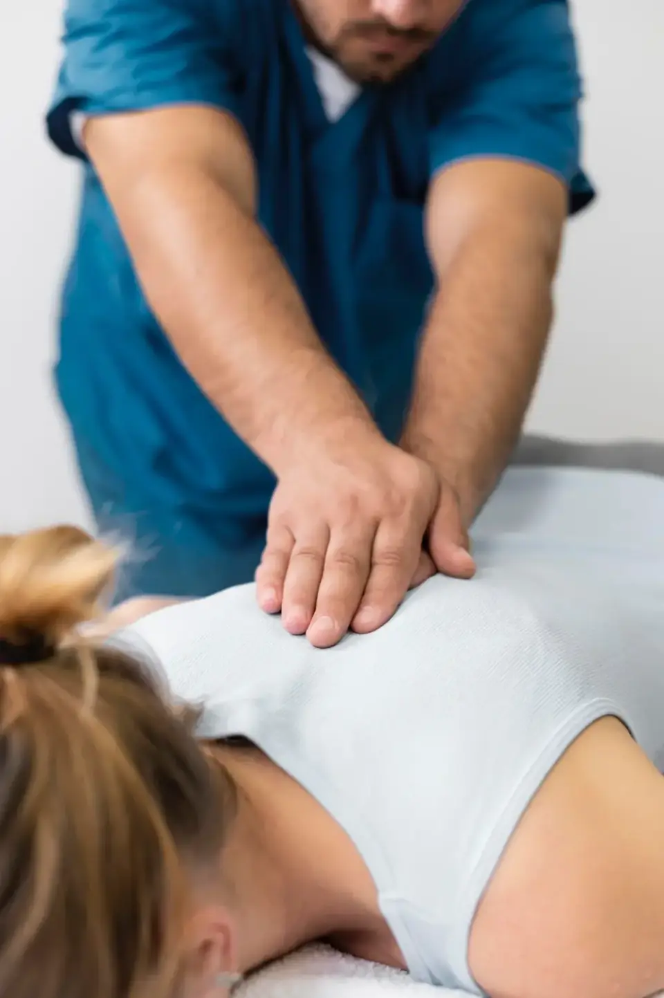 Physiotherapeut behandelt mit den Händen den Rücken einer Patientin